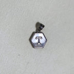 The letter T hexagon pendant on a pale surface.