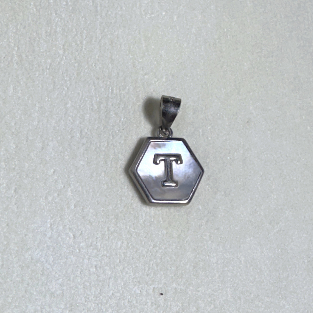 The letter T pendant seen from a slight angle.