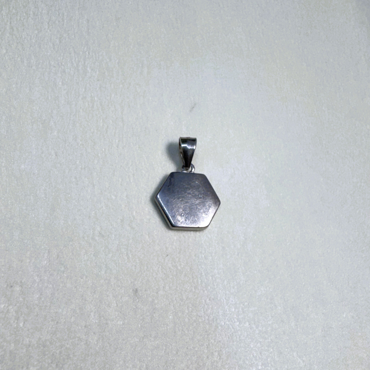 The plain polished silver back of the hexagon initial pendant.