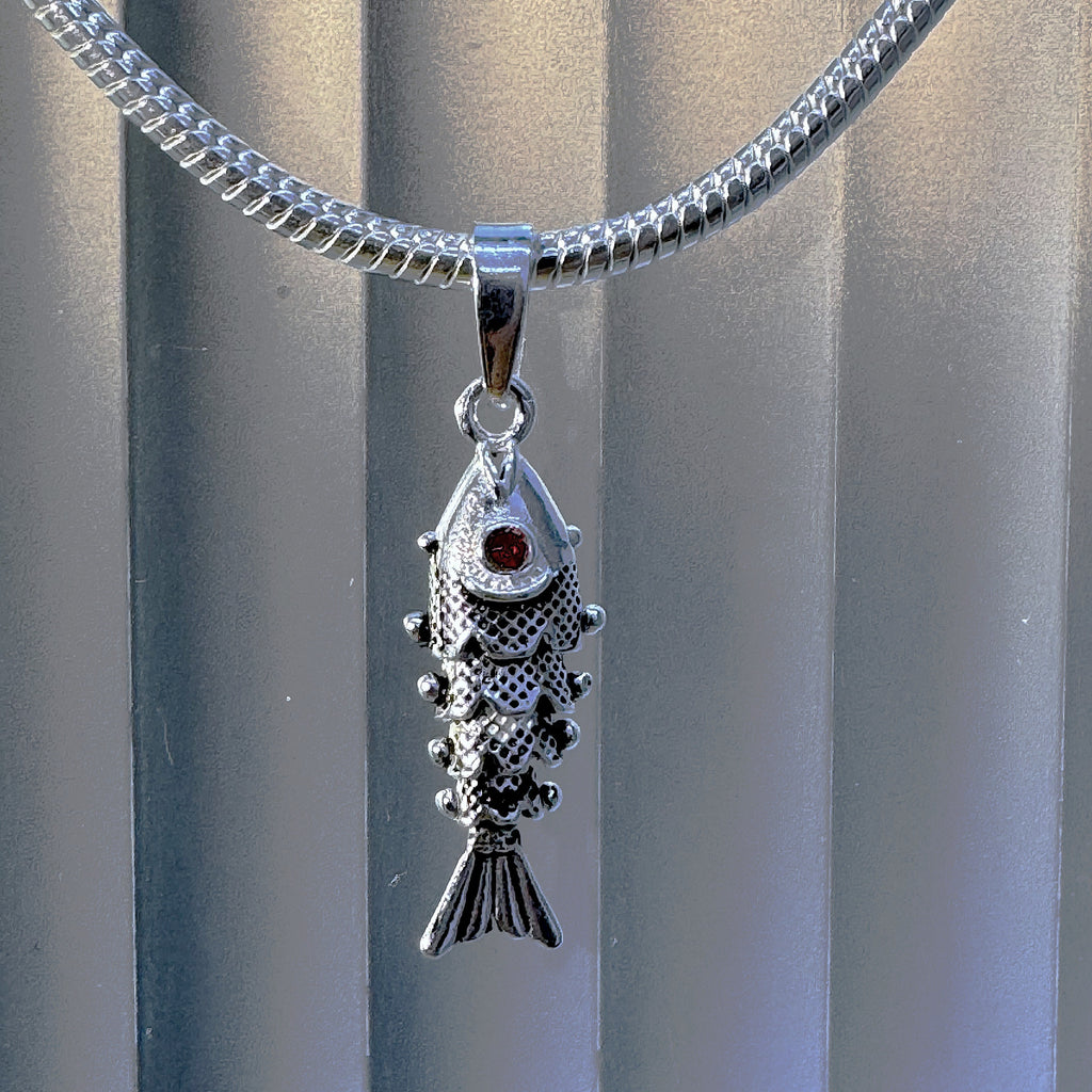 Oxidised sterling silver articulated fish pendant with red stone eyes, hanging on a snake chain. Chain sold separately.