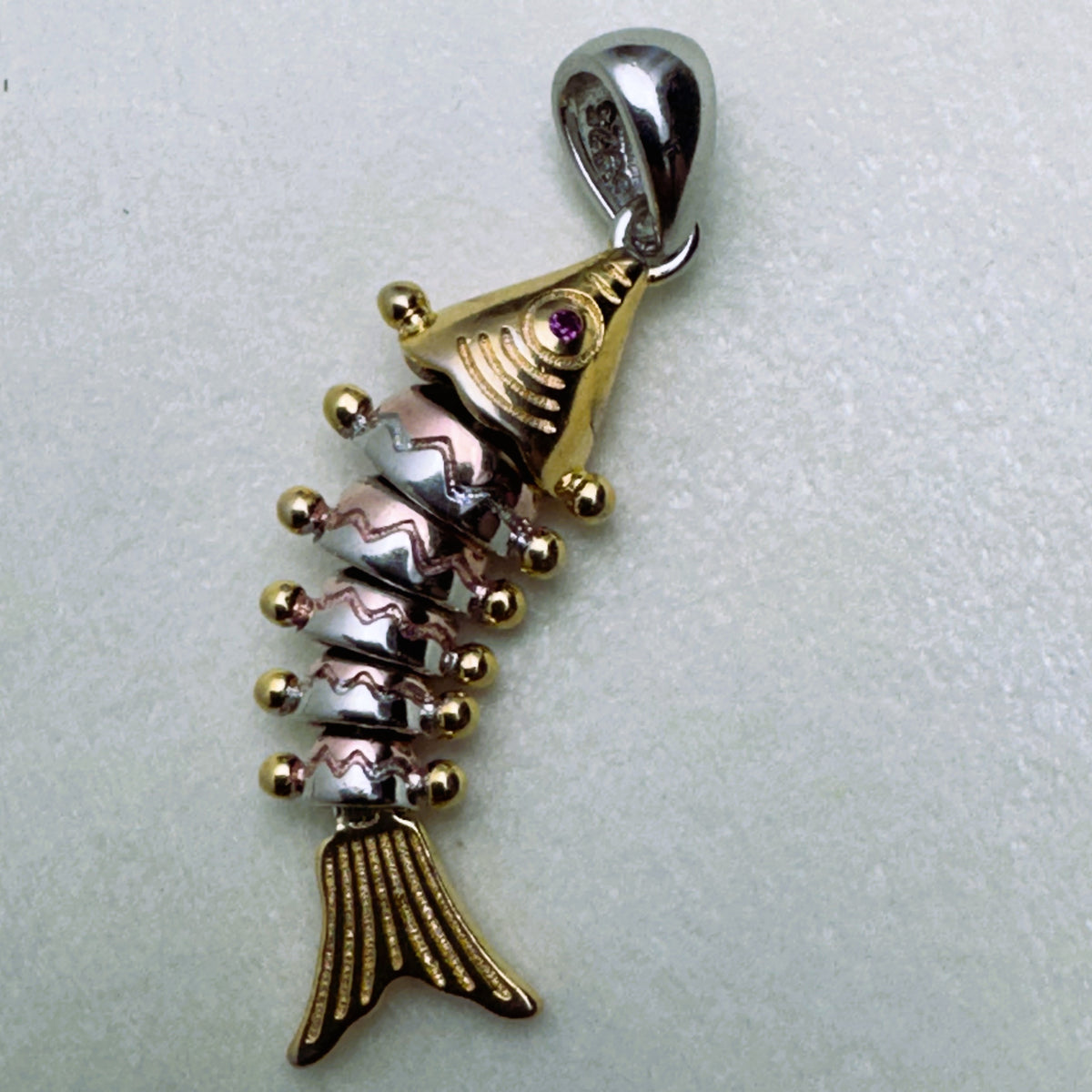 Tri-tone sterling silver articulated fish pendant with a gold-tone head and tail and rose-tone segments.