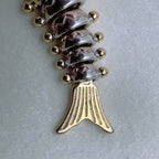 Close view of the gold-tone tail and the rose-tone and silver segments of the fish.
