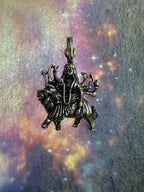Oxidised sterling silver Durga and lion pendant lit from above on a violet iridescent background.