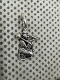Oxidised sterling silver Hanuman pendant holding a gada and a mountain, on white fabric with grey dots.