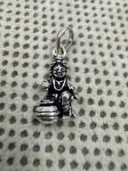 Front view of the sterling silver pendant, showing the seated figure, the raised open hand and the wide-mouthed butter pot.