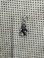 Full length of the sterling silver pendant with its oval bail and jump ring, laid on grey dotted fabric.