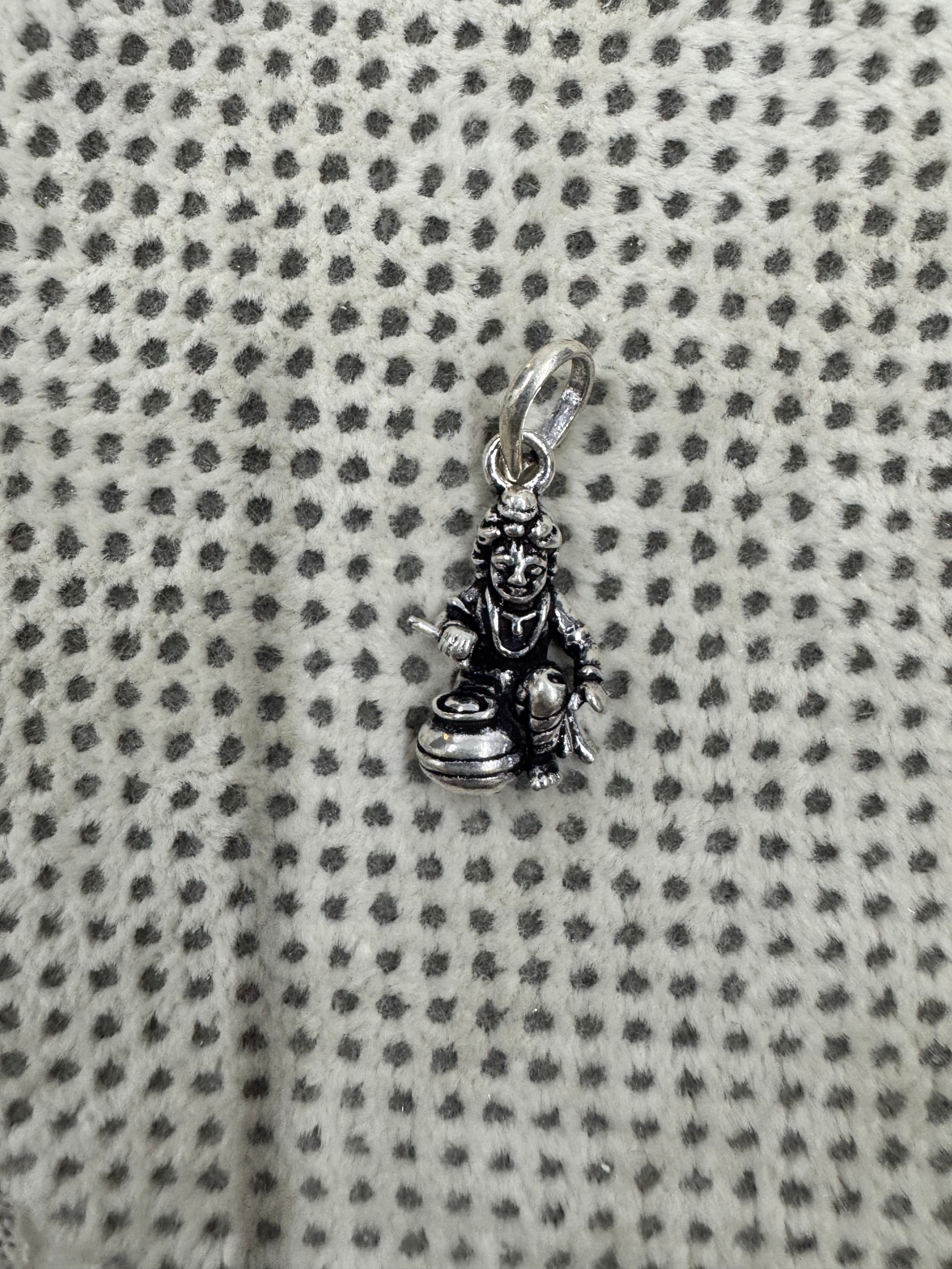 Full length of the sterling silver pendant with its oval bail and jump ring, laid on grey dotted fabric.