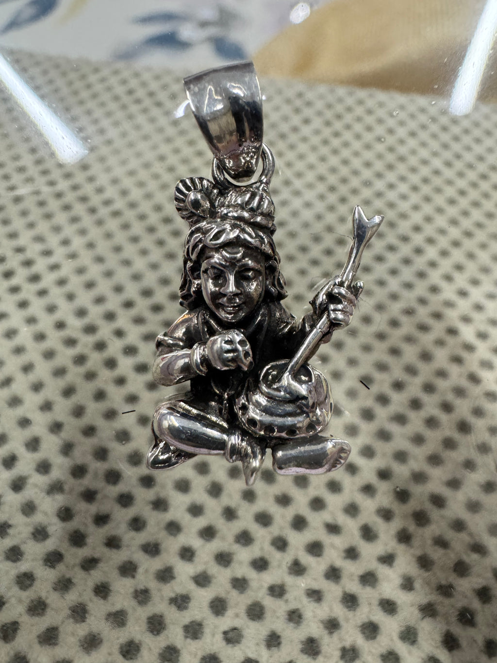 Front view of the sterling silver pendant, one arm raised and gripping a long churning stick.