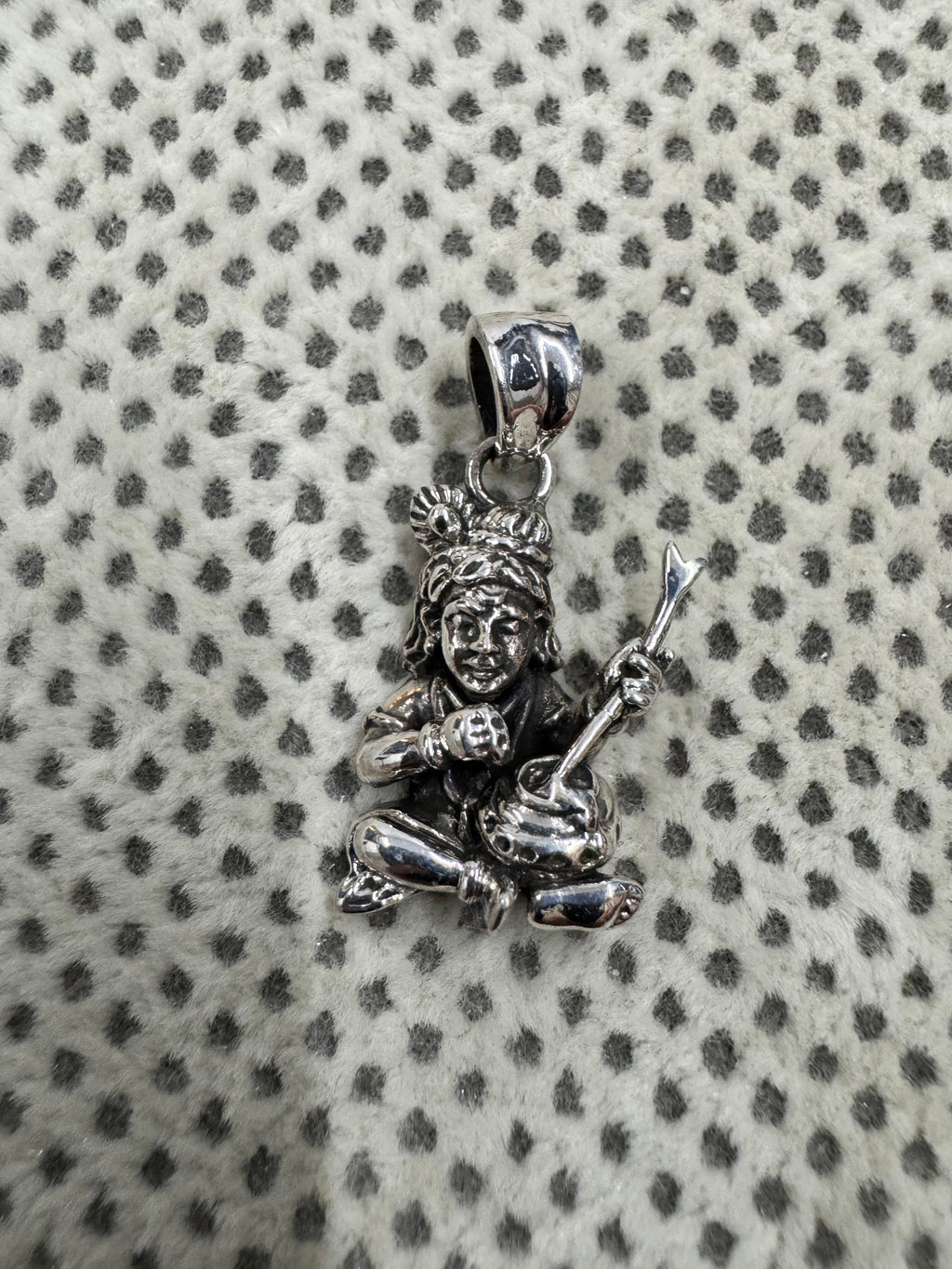 Cast sterling silver pendant showing the crossed legs, a round butter ball in one fist and the flat tapered bail.