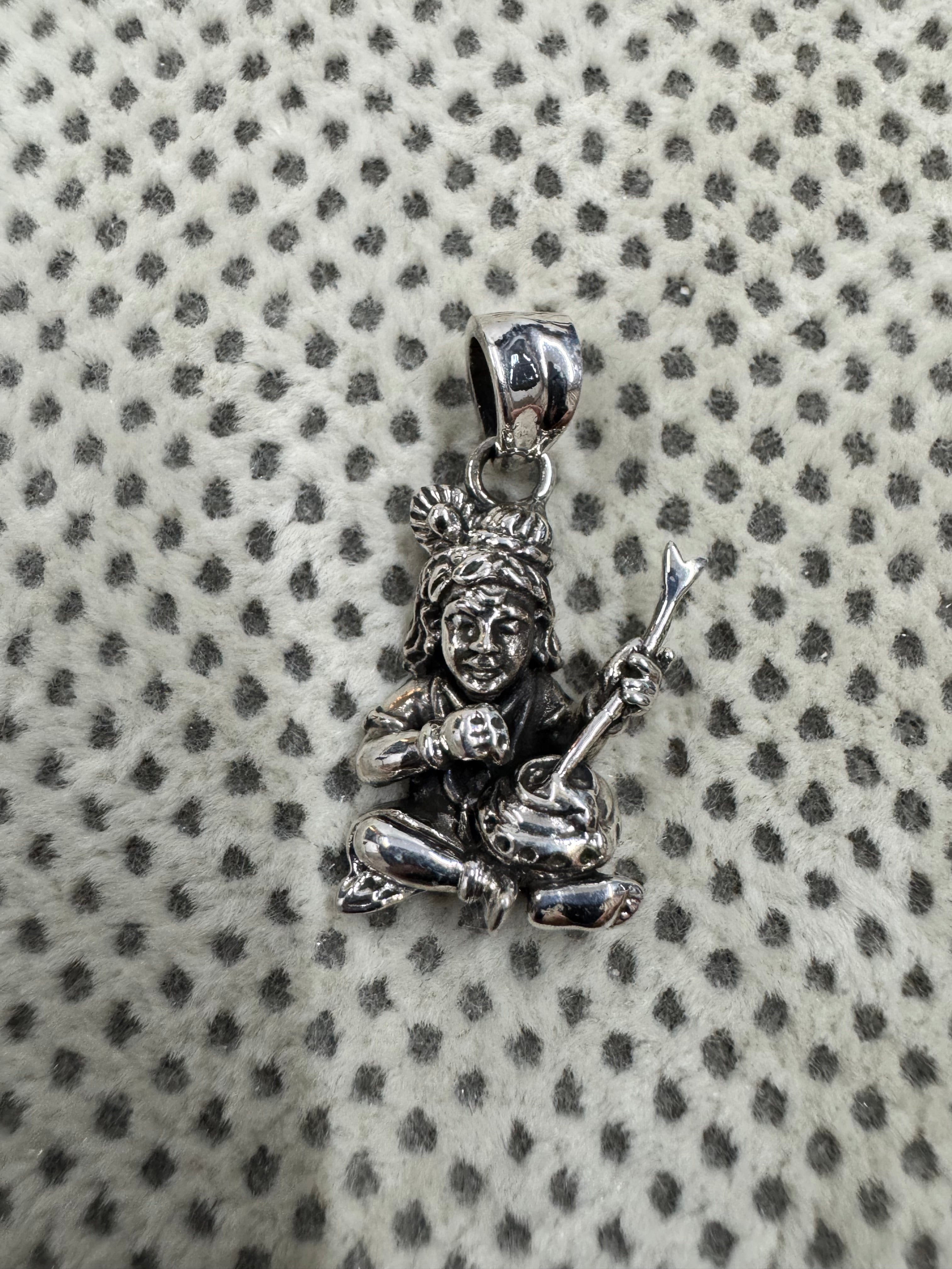 Cast sterling silver pendant showing the crossed legs, a round butter ball in one fist and the flat tapered bail.
