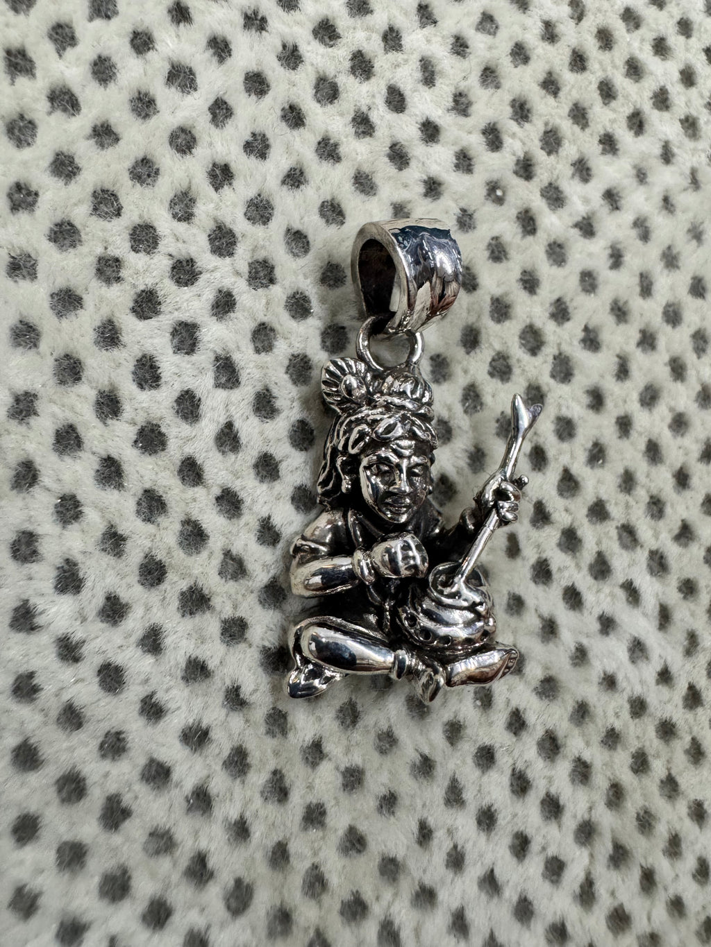 Angled view of the sterling silver pendant, the churning stick set into the mouth of the pot at the figure's lap.