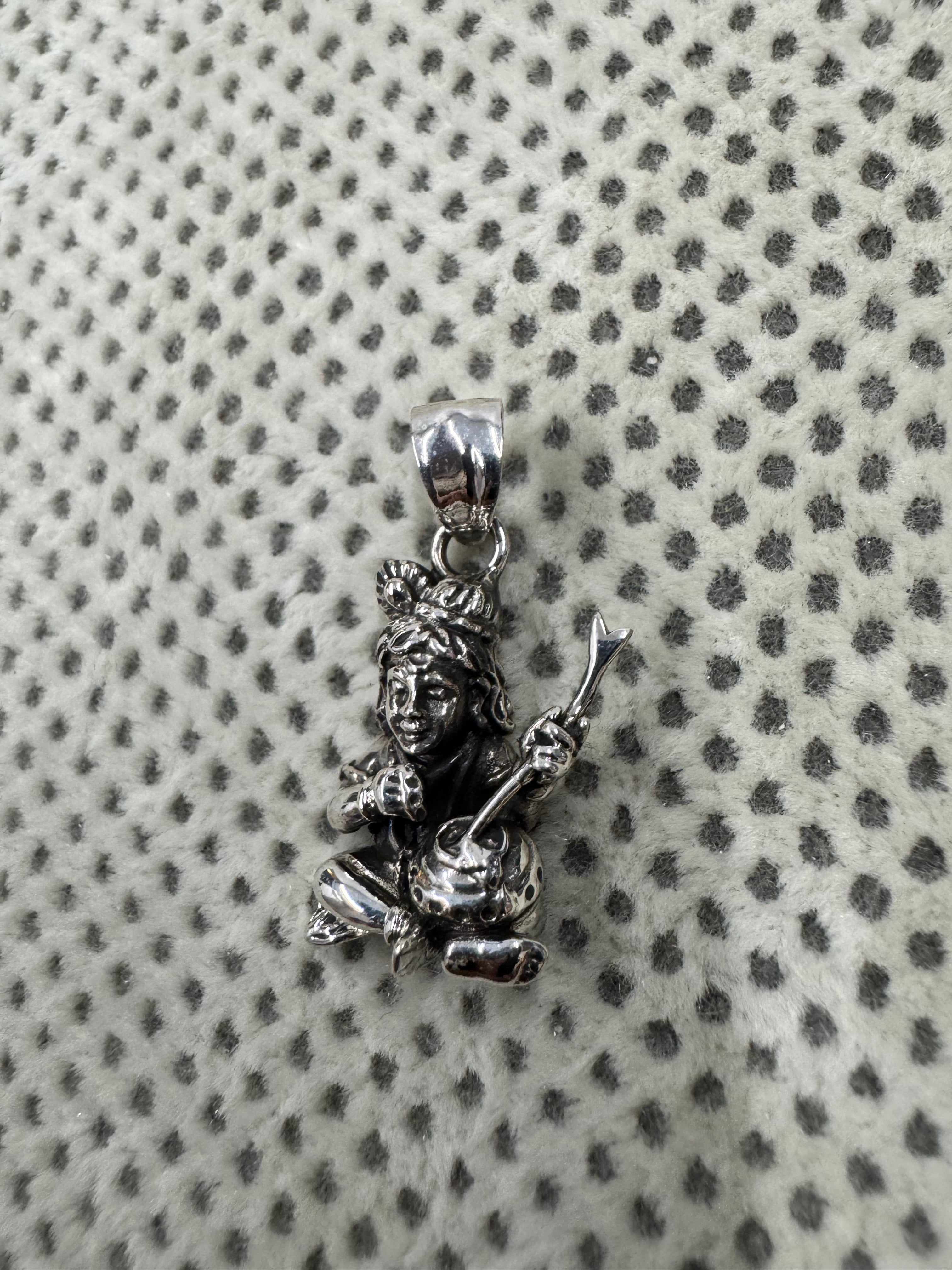 Full length of the sterling silver pendant with its flat tapered bail and jump ring on grey dotted fabric.