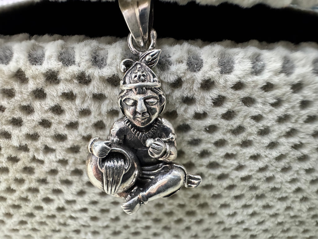 Sterling silver pendant hanging from its flat bail, showing the conical crown with plume and the fluted butter pot.