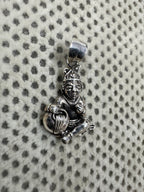 Angled view of the sterling silver pendant, the raised fist and the folded legs seen from the side.