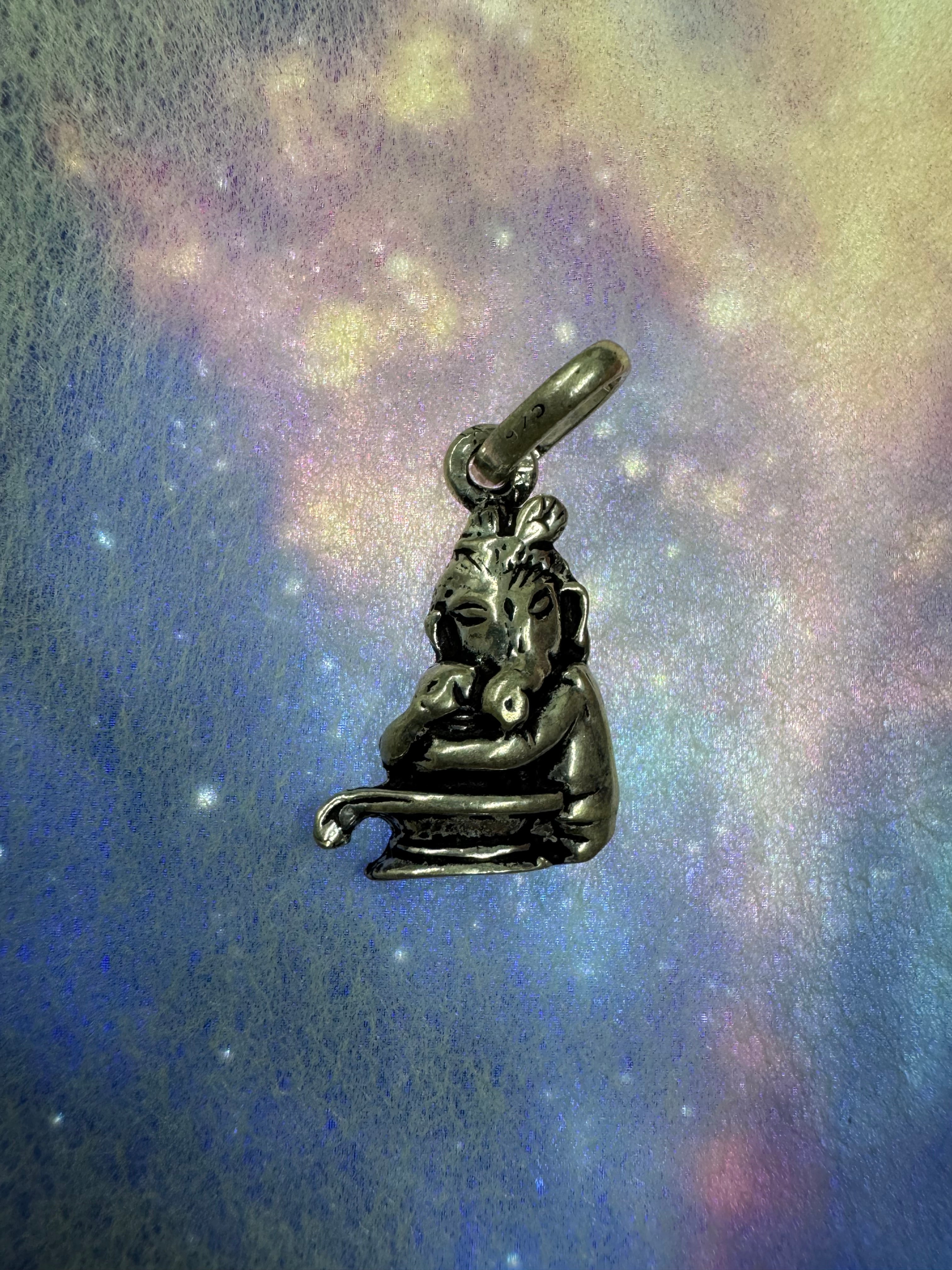Bright sterling silver Ganesha pendant on a blue iridescent backdrop, the oxidation held in the ears and the plinth courses.