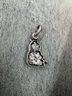 Reverse of the bright sterling silver Ganesha pendant on grey speckled card, showing the hollow casting and the jump ring.