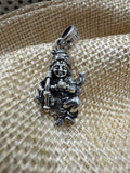Sterling silver krishan pendant seated with a hearding stick, resting on a woven jute backdrop.