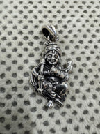 Oxidised sterling silver krishna pendant on grey dotted fabric, showing the topknot, the scored brow.