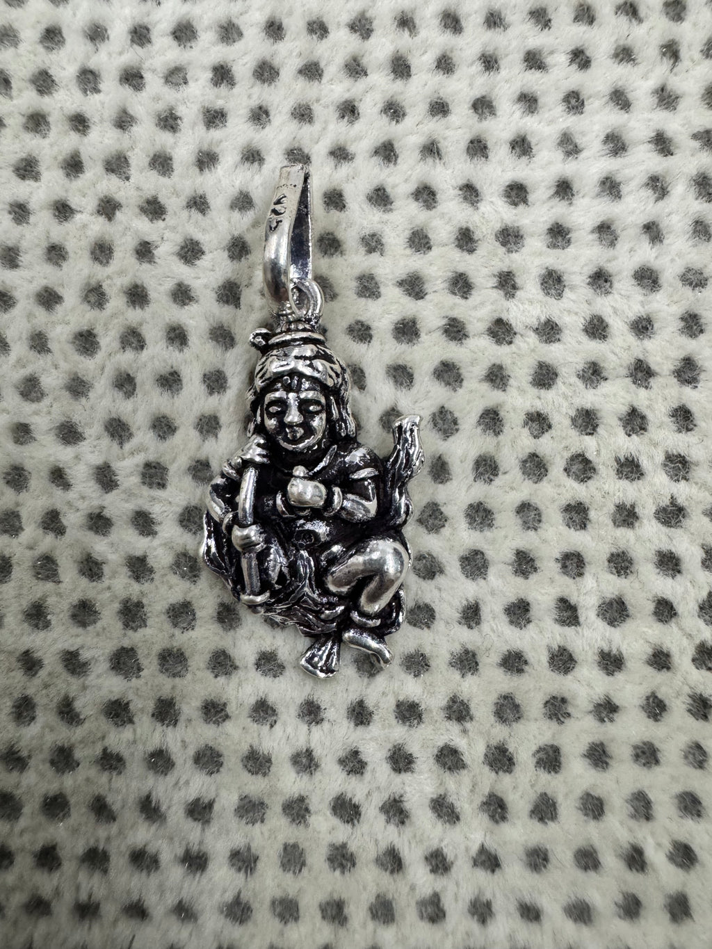 Sterling silver krishan pendant photographed small on dotted fabric to show its proportion beside the bail.