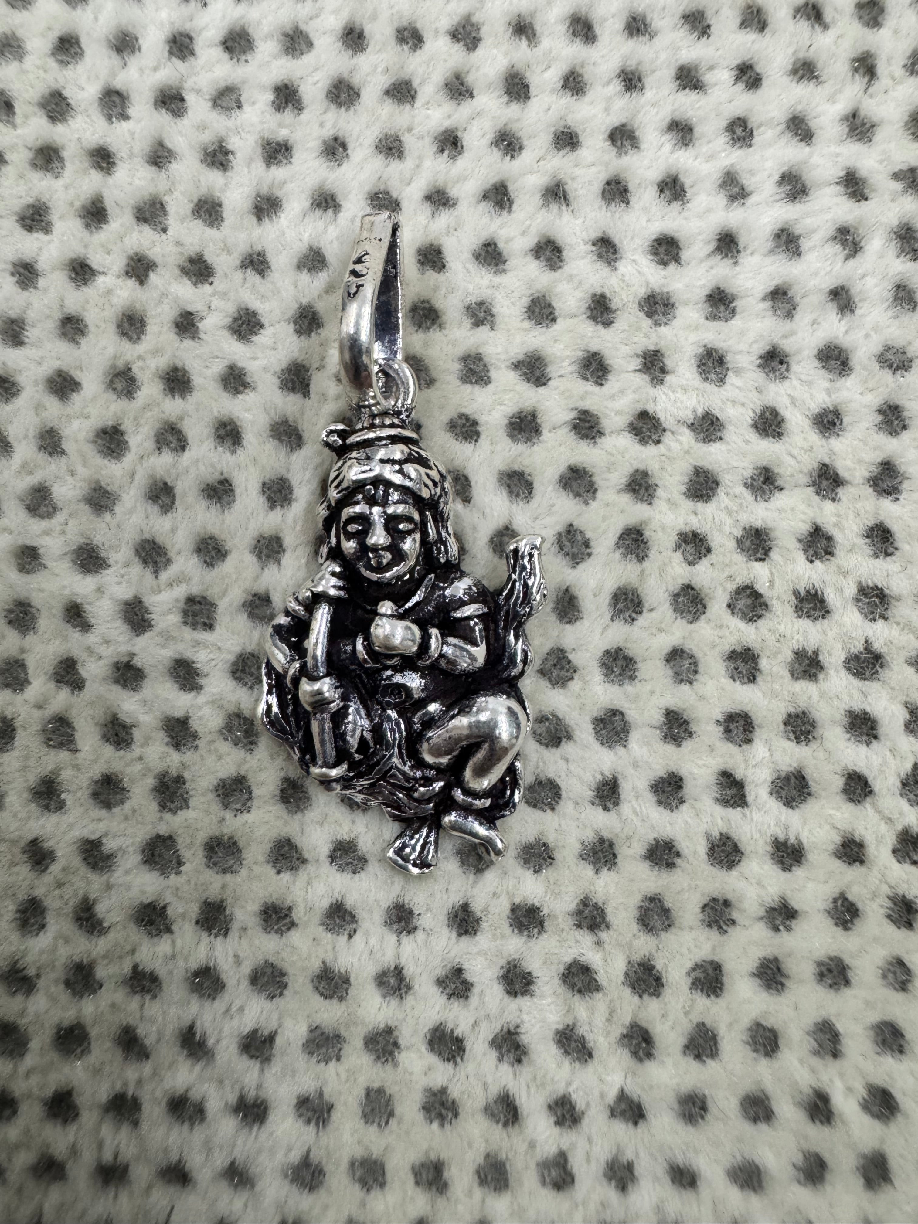 Sterling silver krishan pendant photographed small on dotted fabric to show its proportion beside the bail.