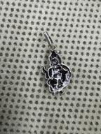 Reverse of the sterling silver gwala krishan pendant on dotted fabric, showing the hollowed back of the casting.