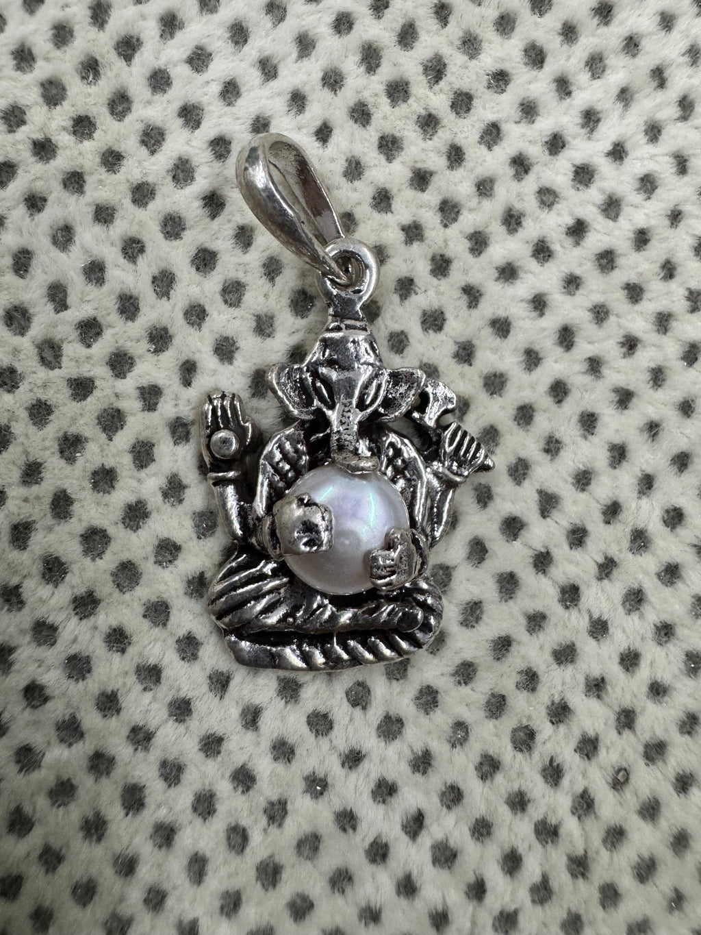 Close view of the pearl in its four cast claws on the sterling silver Ganesha pendant, with the oval bail loop alongside.