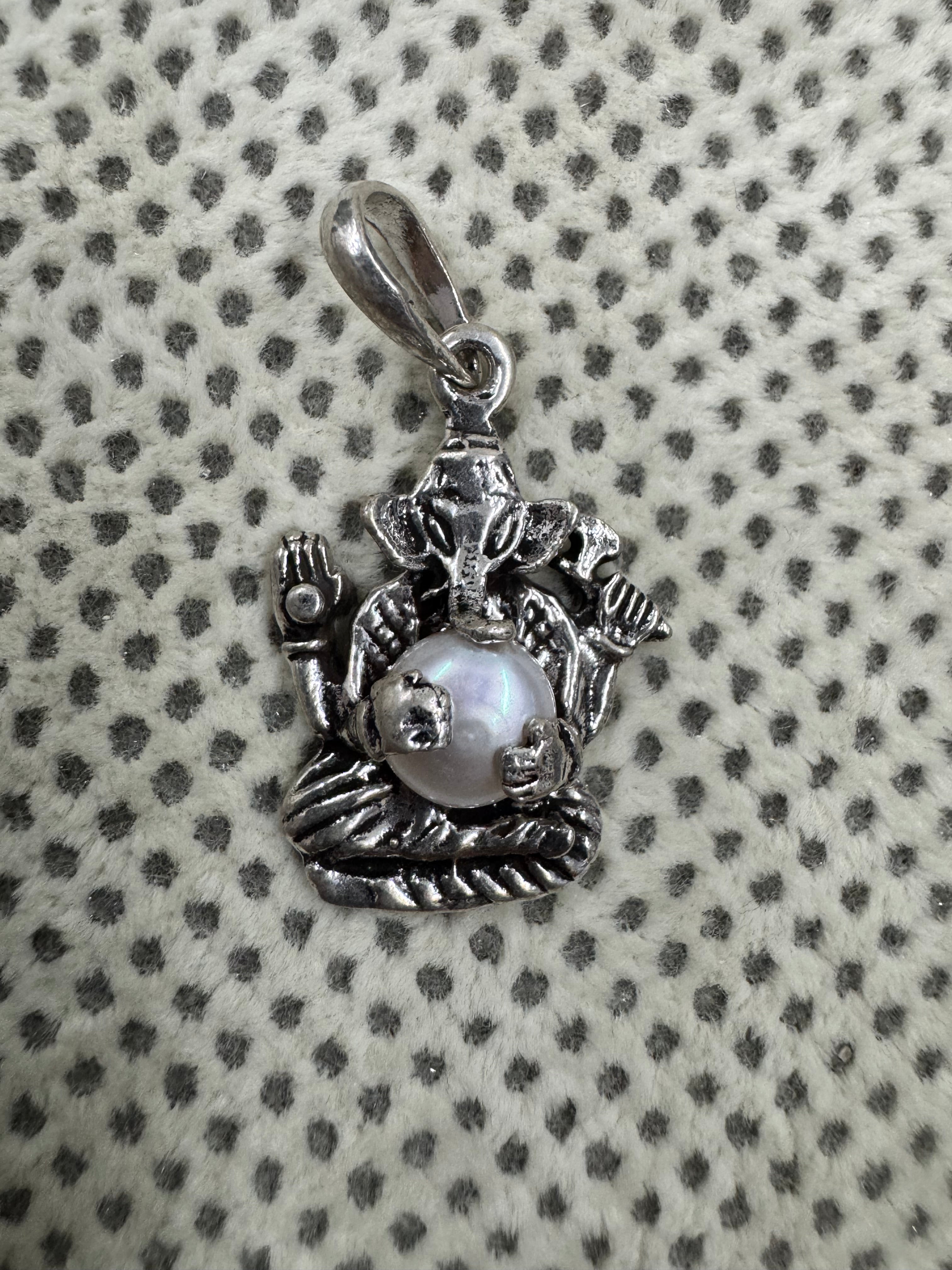Close view of the pearl in its four cast claws on the sterling silver Ganesha pendant, with the oval bail loop alongside.