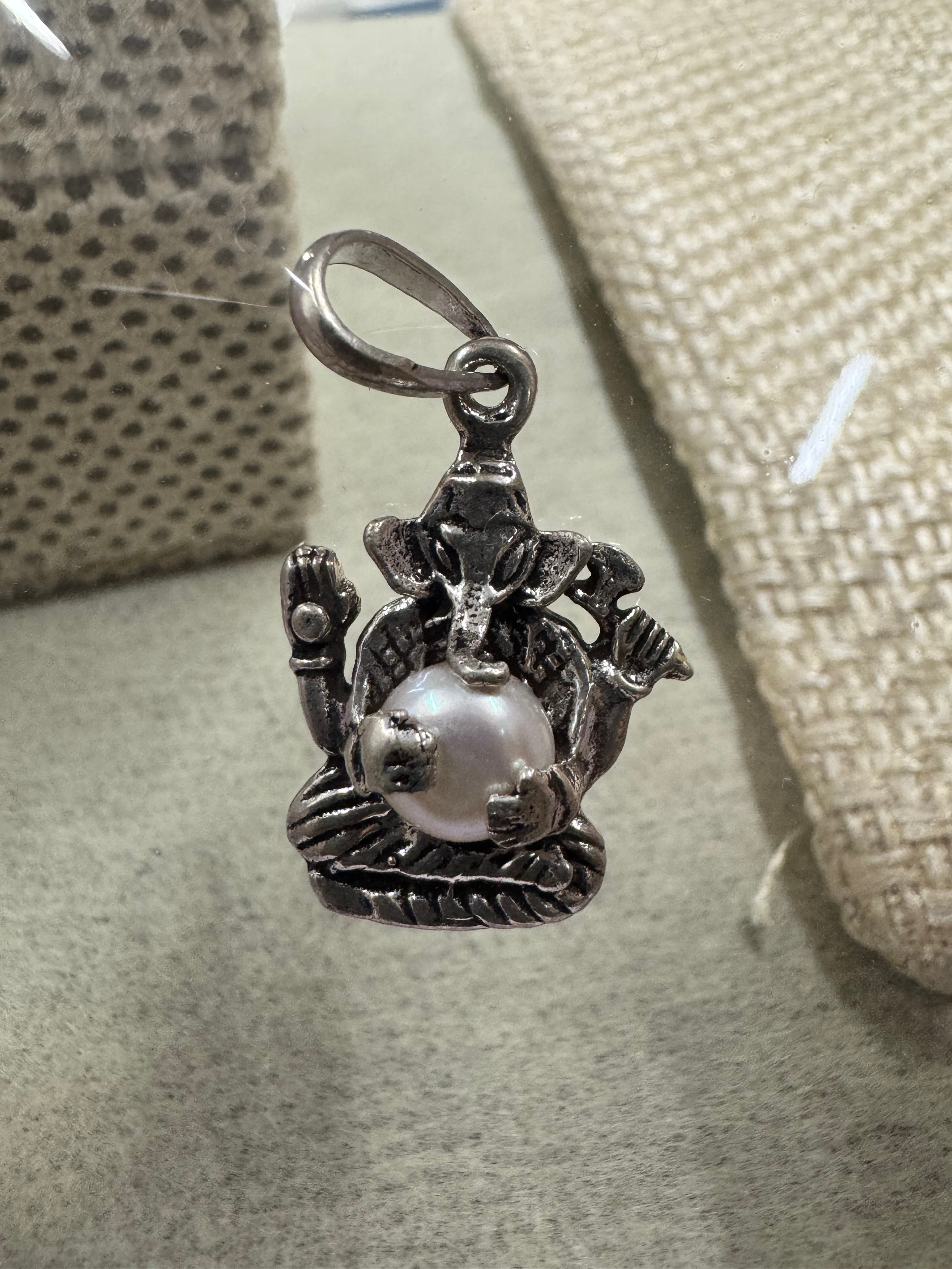 Sterling silver Ganesha pendant with pearl on a grey-green card, a jute weave behind it.