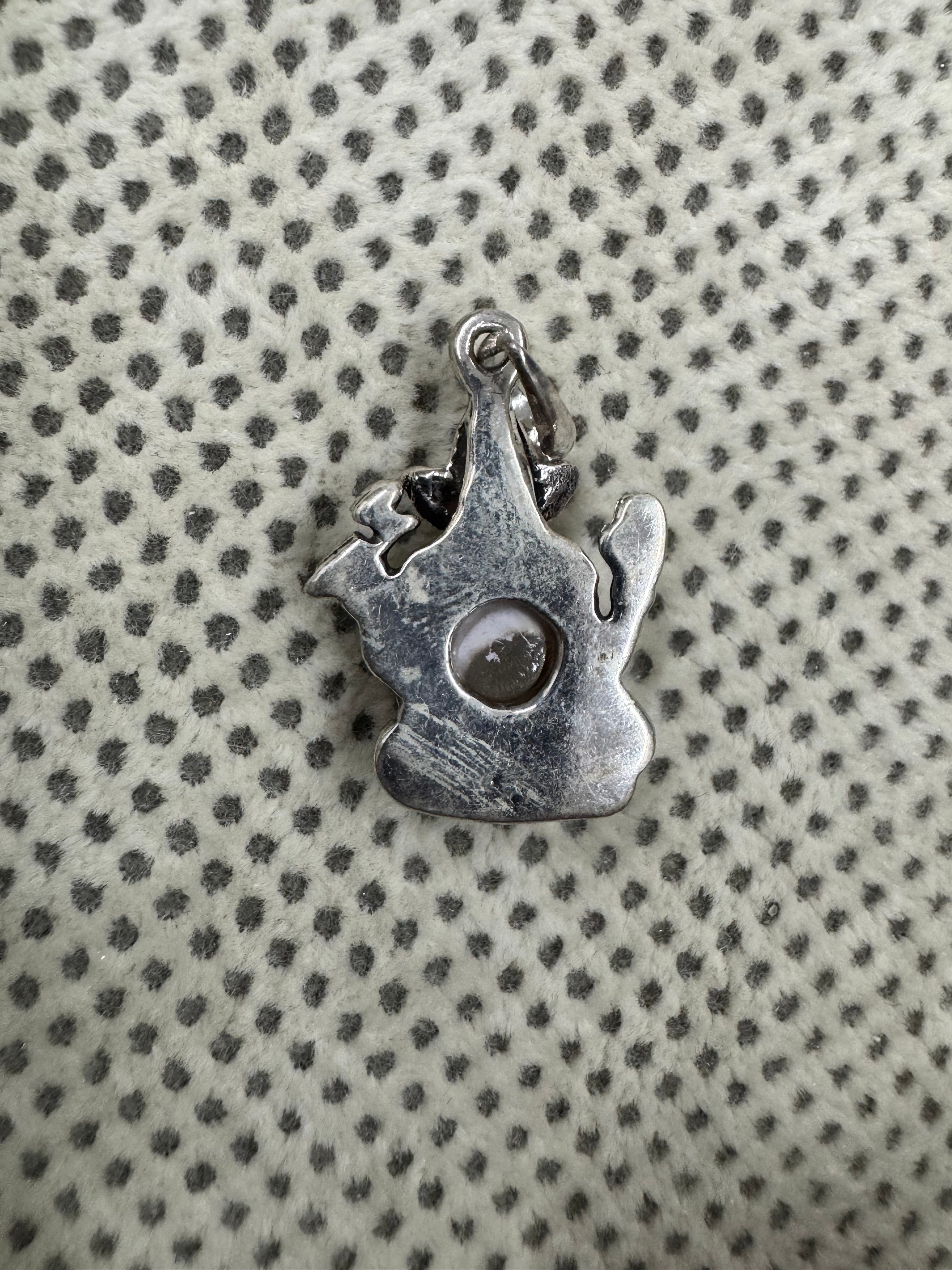 Reverse of the sterling silver Ganesha pendant on dotted fabric, the open back showing the underside of the pearl.
