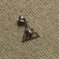 Sterling silver openwork triangle Pendant with a red bead at its centre, photographed flat on beige woven fabric.