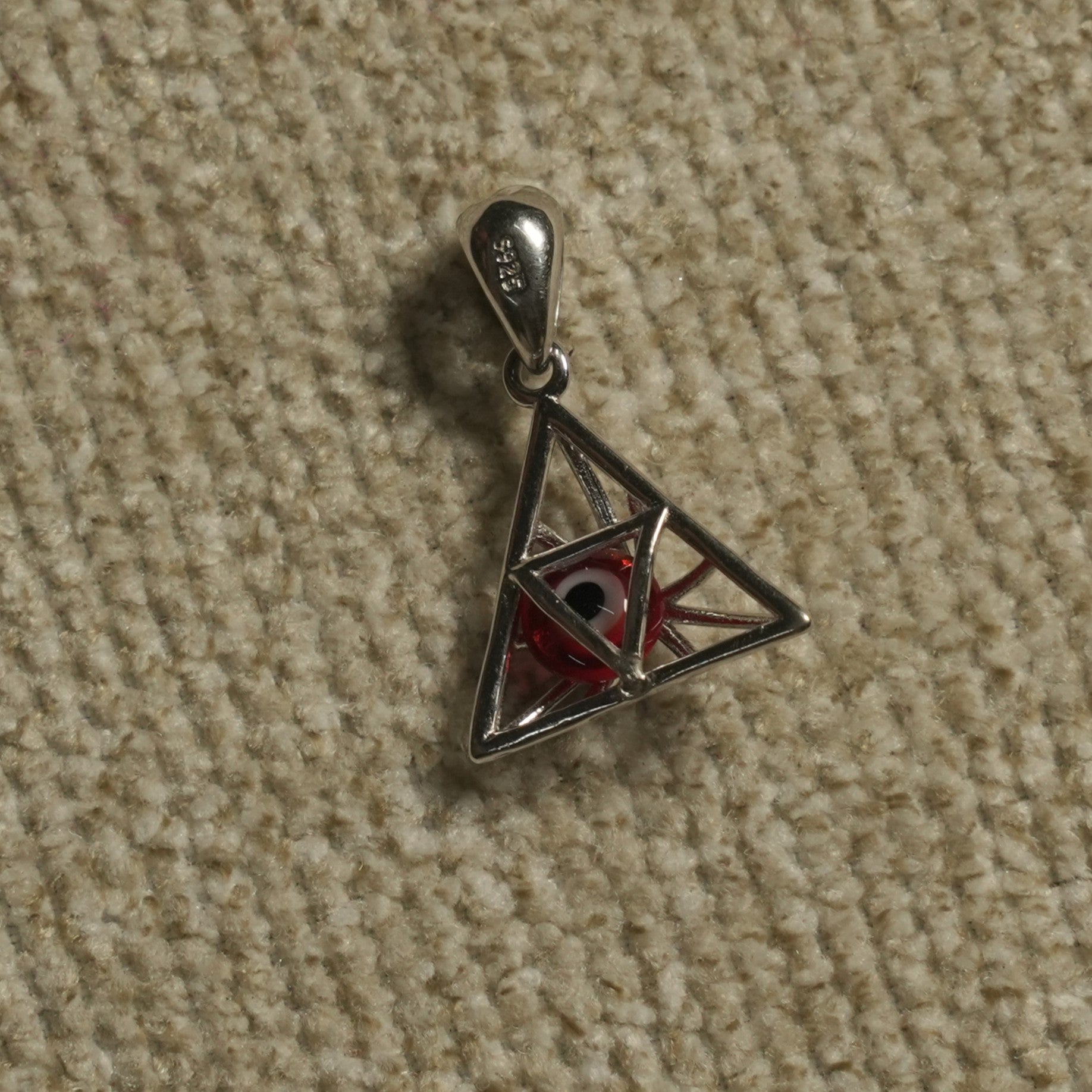 Reverse of the sterling silver triangle Pendant revealing the red-and-white eye bead held within the frame.