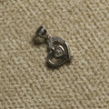 Sterling silver Pendant of an open heart holding a smaller Bejewelled cubic zirconia heart, photographed on beige woven fabric.