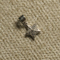 Faceted sterling silver star Pendant set with Bejewelled cubic zirconia, photographed on beige woven fabric.