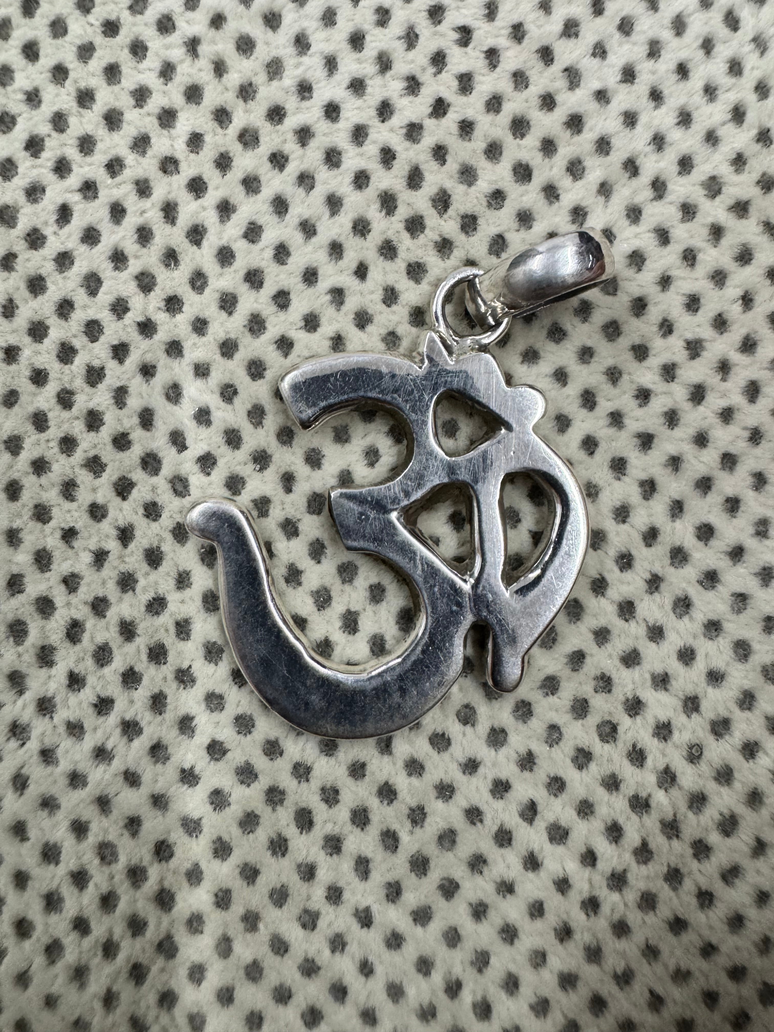 Openwork Om pendant in 925 sterling silver at an angle, the mirror-polished curves catching the light.