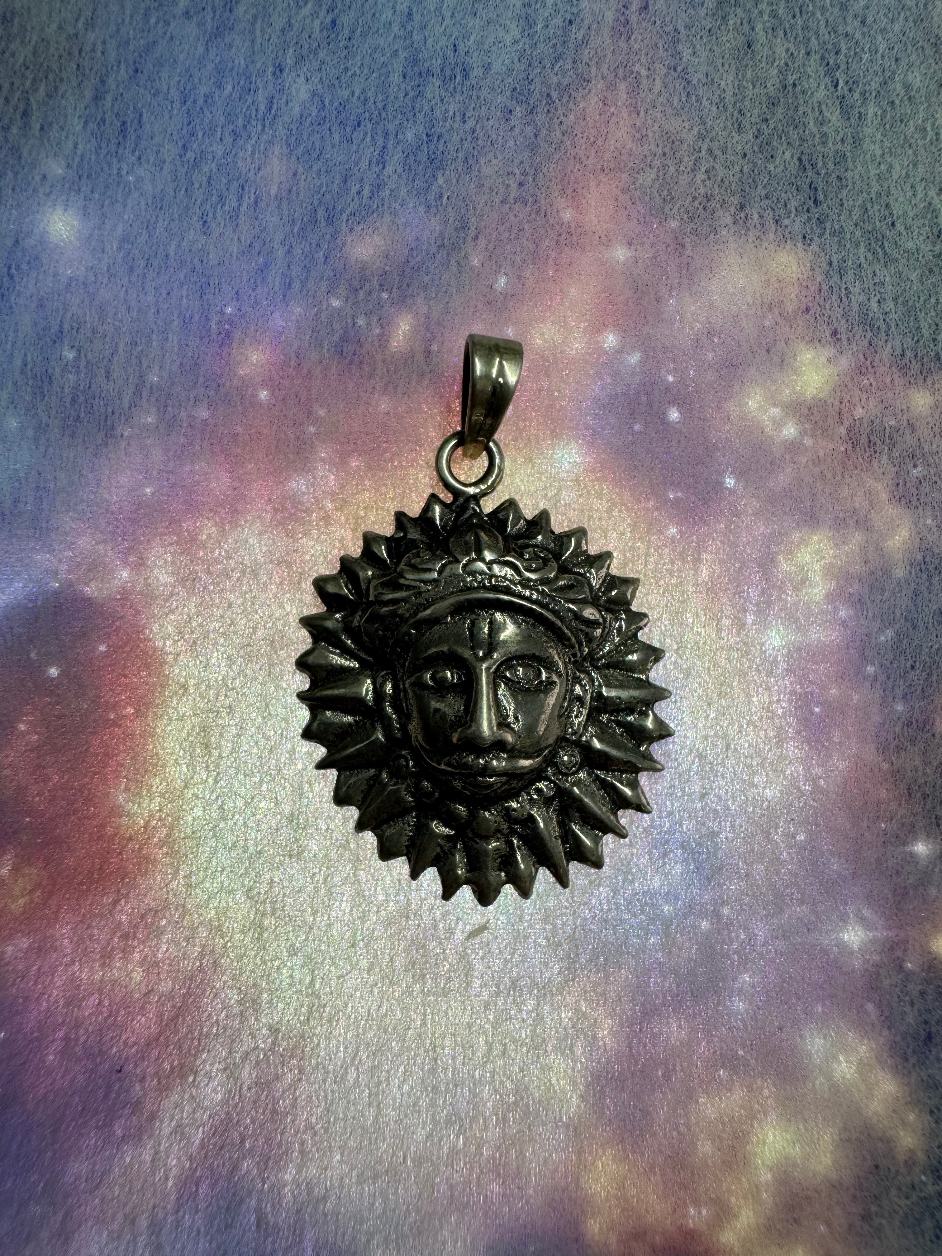Sterling silver sun disc pendant on a blue and violet iridescent backdrop, the flat bail and jump ring at the rim.
