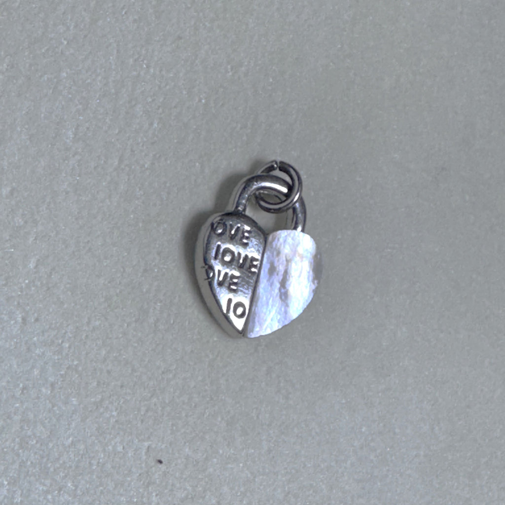The silver heart padlock charm on a grey surface, showing the ring at the top.