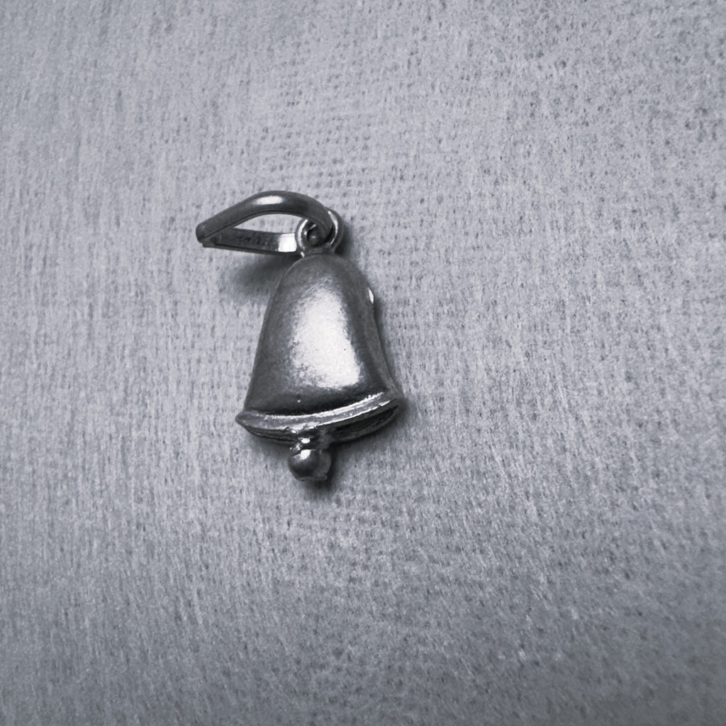 The oxidised silver bell charm seen from the front, flared rim and clapper below.