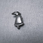 The oxidised silver bell charm seen from the front, flared rim and clapper below.