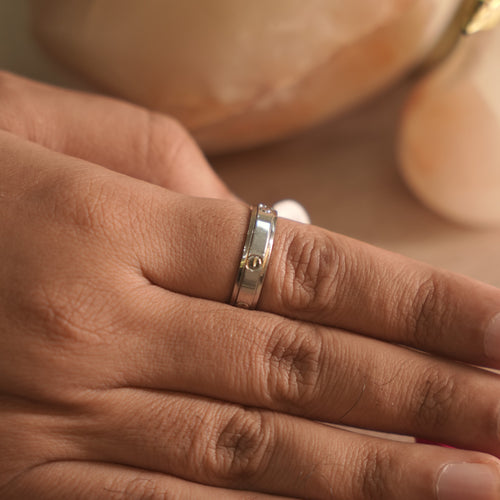 Polished sterling silver spinner band ring with screw motifs engraved on its rotating centre.