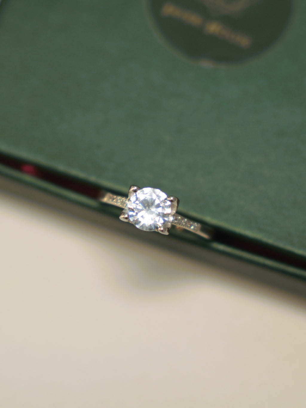 Top view of the round American Diamond solitaire ring, showing the pave set shoulders.