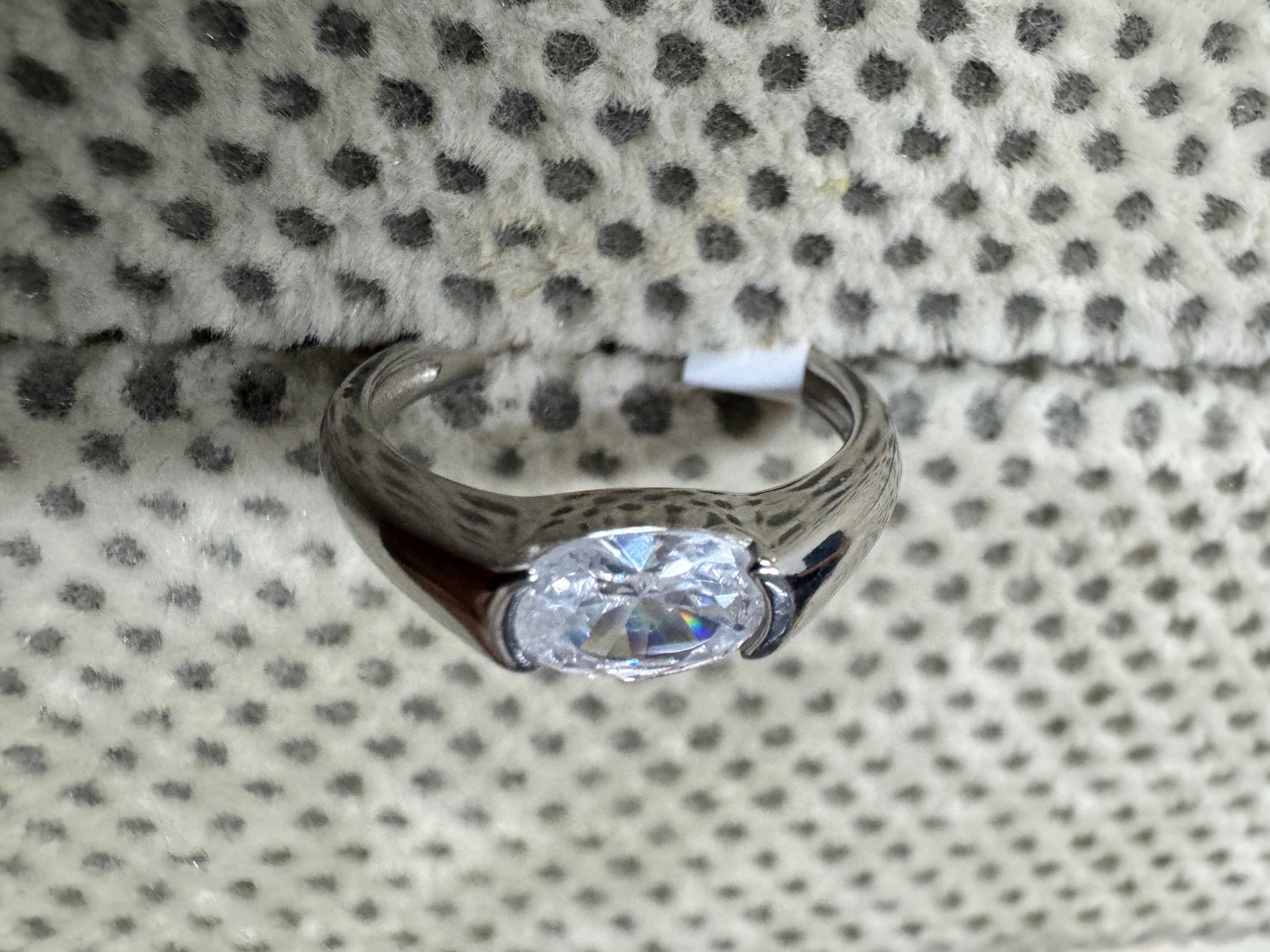 Front view of the sterling silver ring, showing the oval cubic zirconia held between two half-bezel shoulders.