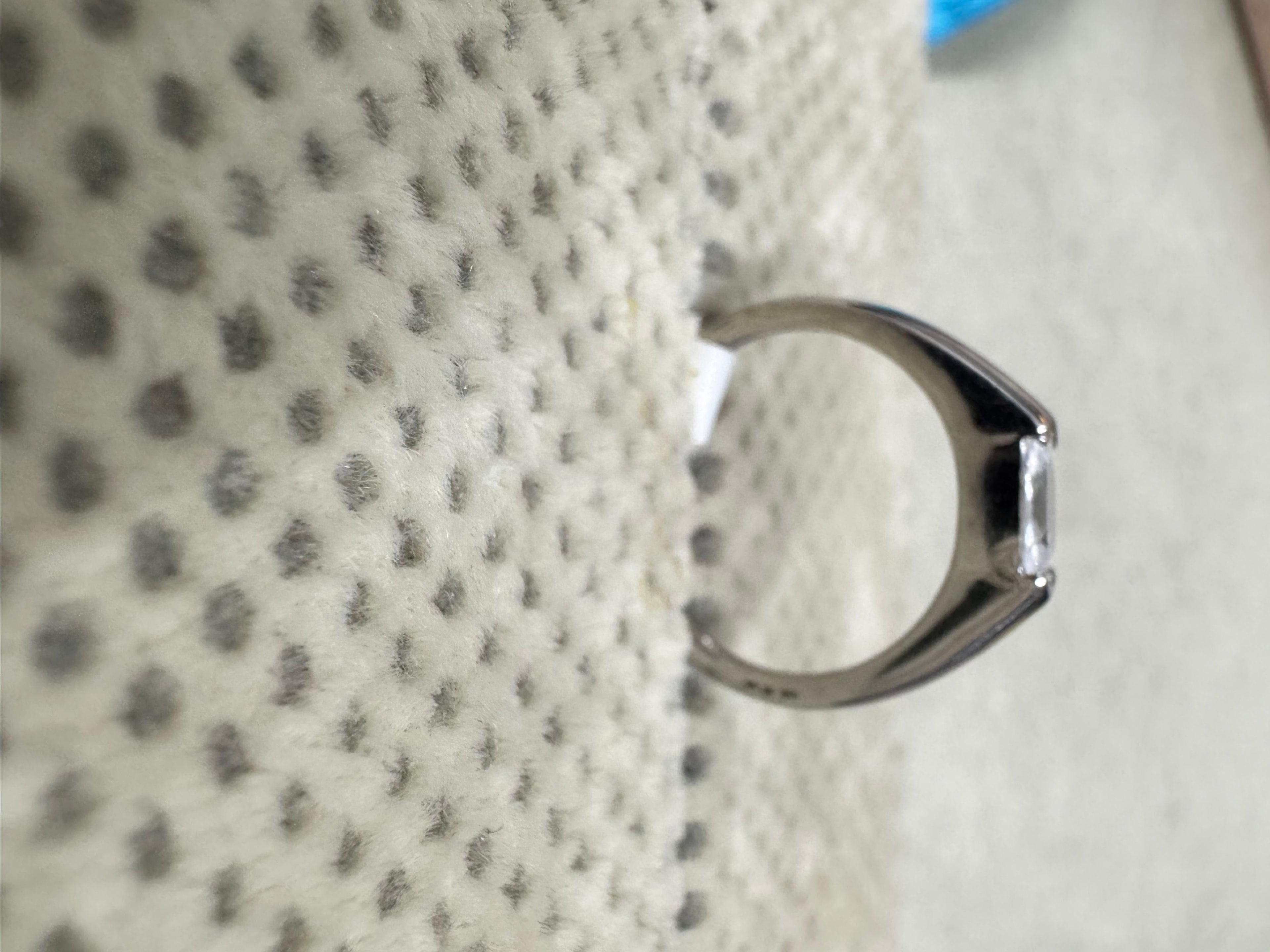 Profile of the sterling silver ring against textured fabric, showing the cathedral rise of the shoulders into the setting.
