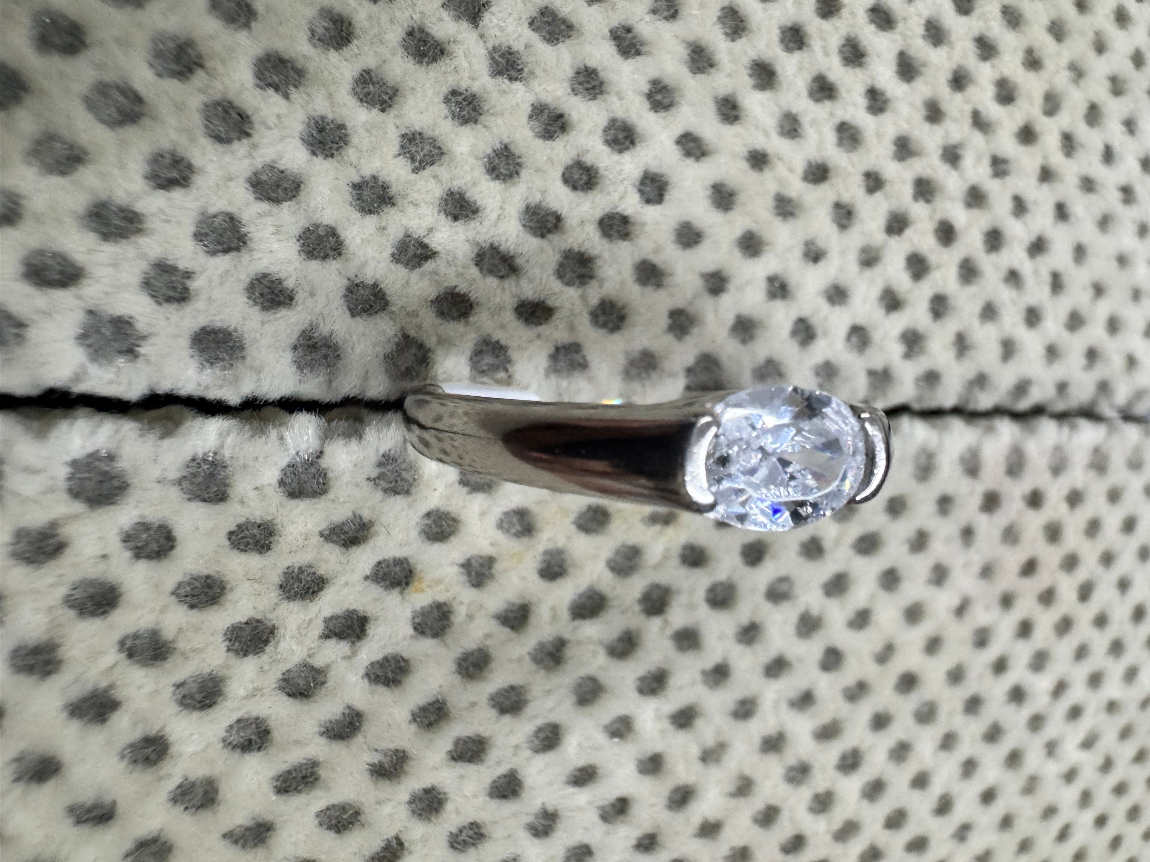 Angled view of the sterling silver ring, showing a polished shoulder sweeping into the half-bezel around the cubic zirconia.