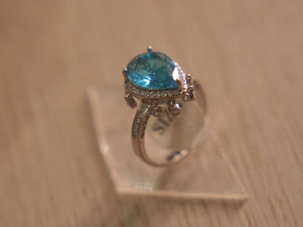 Angled view of the sky blue stone ring, showing the stone set shoulders and swinging drops.