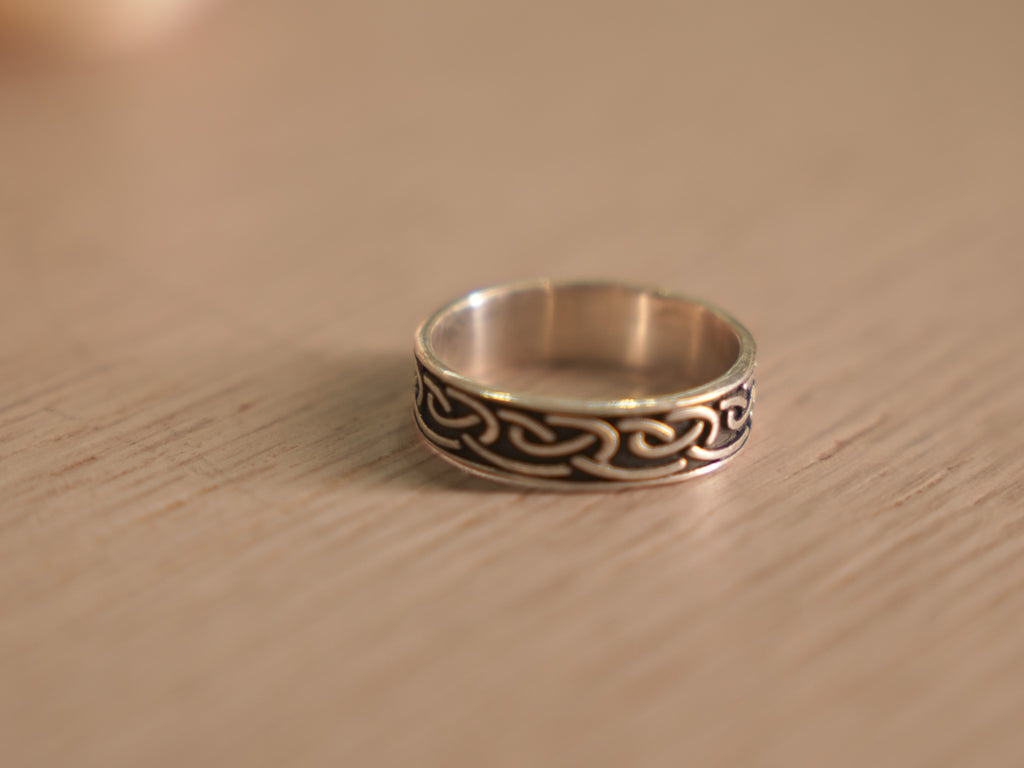 Close view of the Viking knot band, showing the dark recesses against polished ridges.