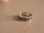 Close view of the Viking knot band, showing the dark recesses against polished ridges.