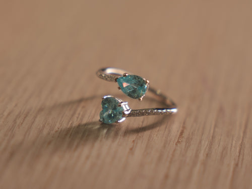 Sterling silver bypass ring with a sky blue pear shaped glass stone and a blue heart at the crossing.