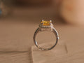 Sterling silver halo ring with a cushion cut vivid yellow glass stone in a four prong setting.
