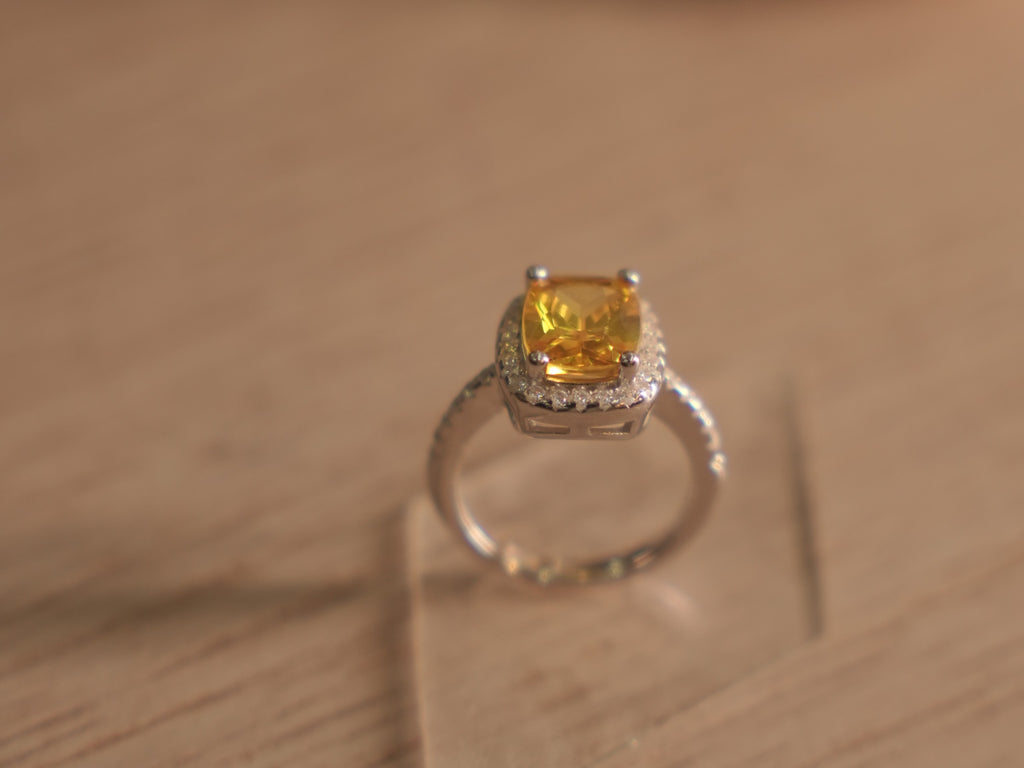 Close view of the yellow glass stone and colourless halo above the faceted band.