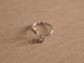 Open sterling silver ring with a round American Diamond in a six prong crown facing a small bezel accent.